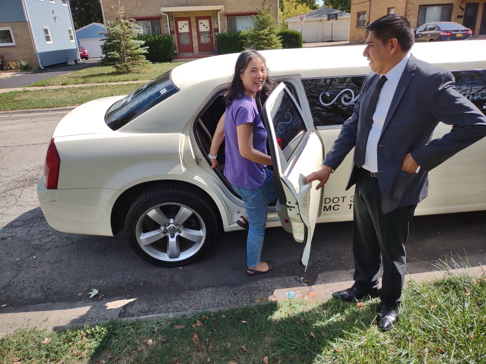 Chauffeur greeting a passenger beside a white stretch limousine, Lake County Limo curbside pickup